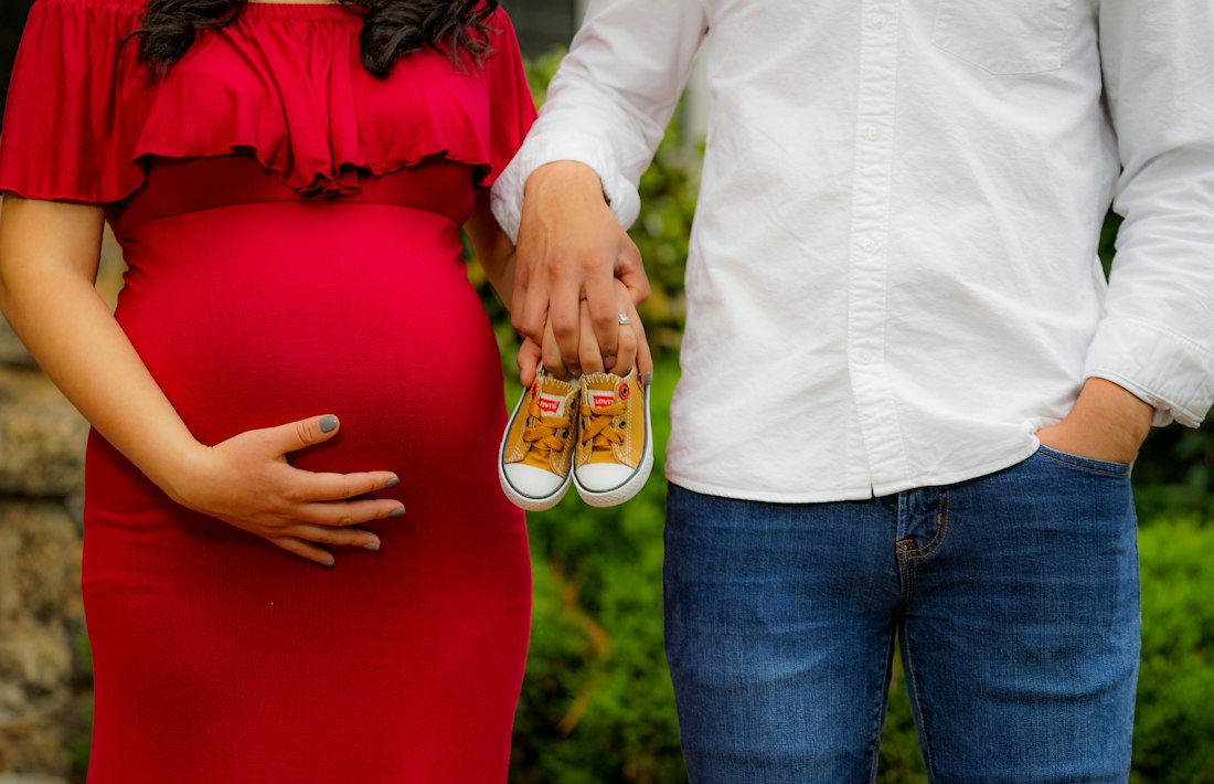 Pareja esperando un bebé sostiene unas zapatillas pequeñas