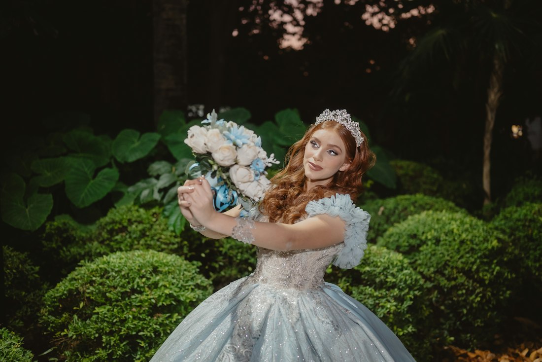 Quinceañera con vestido azul y ramo de flores