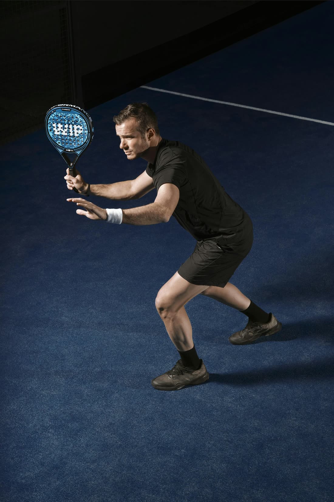 Jugador de pádel preparando un golpe en pista azul